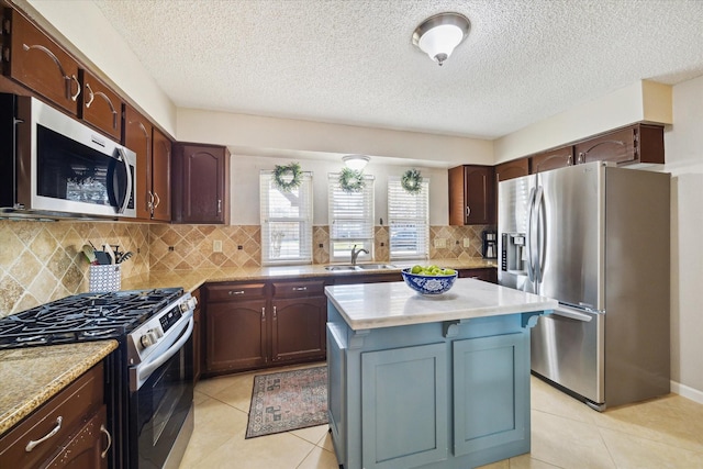 kitchen featuring light tile patterned floors, stainless steel appliances, light countertops, backsplash, and a sink