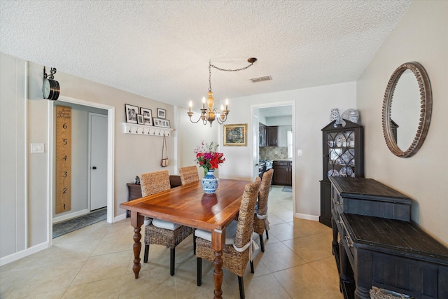 dining space featuring light tile patterned flooring, visible vents, a textured ceiling, and an inviting chandelier