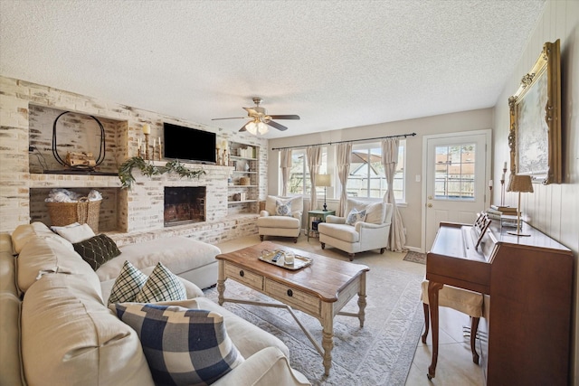 living area with ceiling fan, a fireplace, built in features, and a textured ceiling