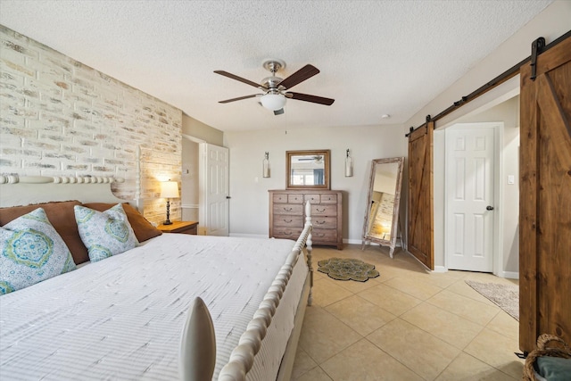 bedroom with light tile patterned floors, a barn door, a ceiling fan, and a textured ceiling