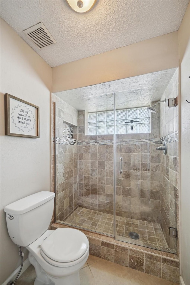 full bathroom with visible vents, toilet, a shower stall, a textured ceiling, and tile patterned flooring