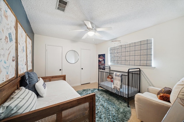 carpeted bedroom with a ceiling fan, visible vents, and a textured ceiling