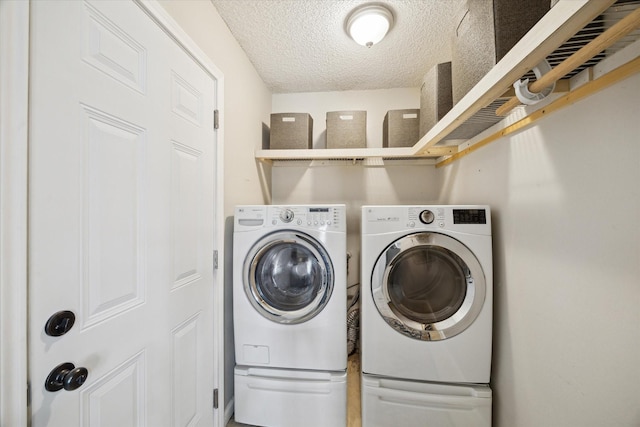 clothes washing area with washer and dryer, laundry area, and a textured ceiling