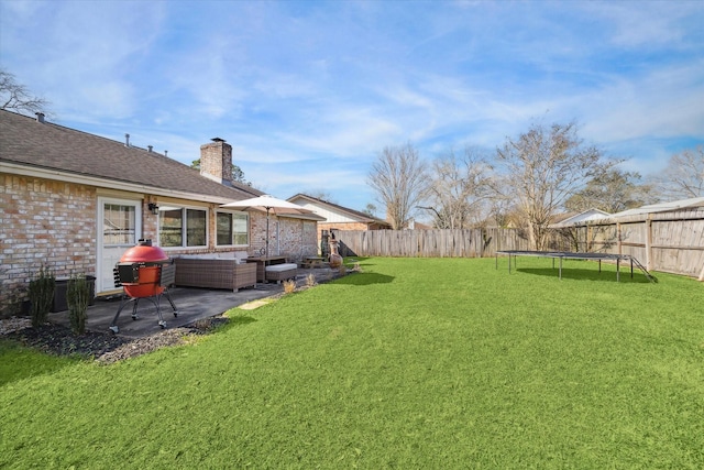 view of yard featuring a trampoline, a fenced backyard, and a patio