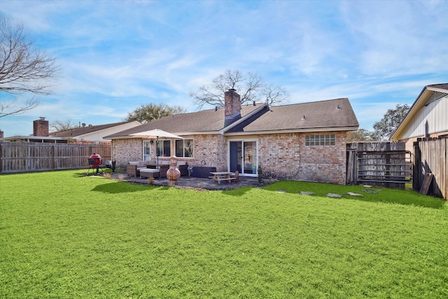 back of house with a yard, a fenced backyard, a chimney, and brick siding