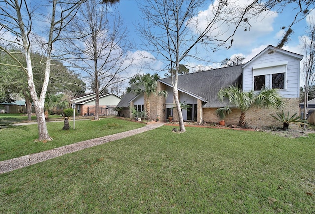 mid-century modern home featuring a front yard, brick siding, and roof with shingles