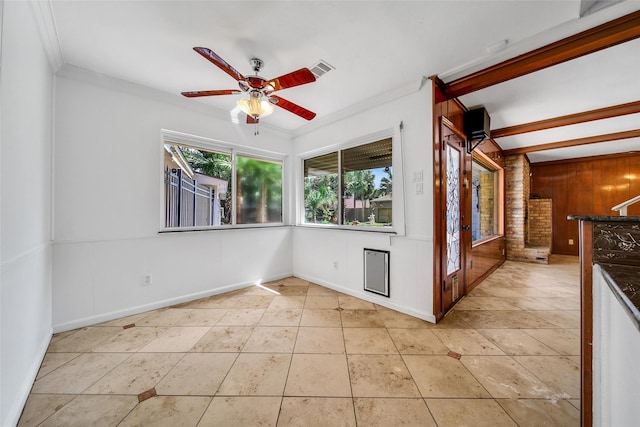 unfurnished room with wooden walls, visible vents, a ceiling fan, and ornamental molding