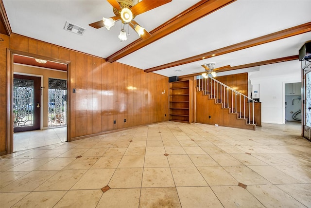 spare room with wooden walls, stairway, visible vents, beam ceiling, and ceiling fan