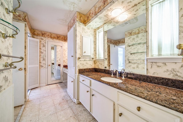 full bath featuring vanity, visible vents, baseboards, wallpapered walls, and a wealth of natural light