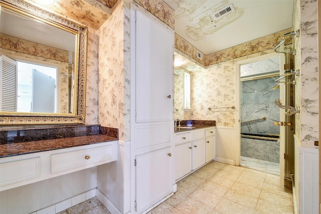 full bathroom featuring a wainscoted wall, visible vents, and wallpapered walls