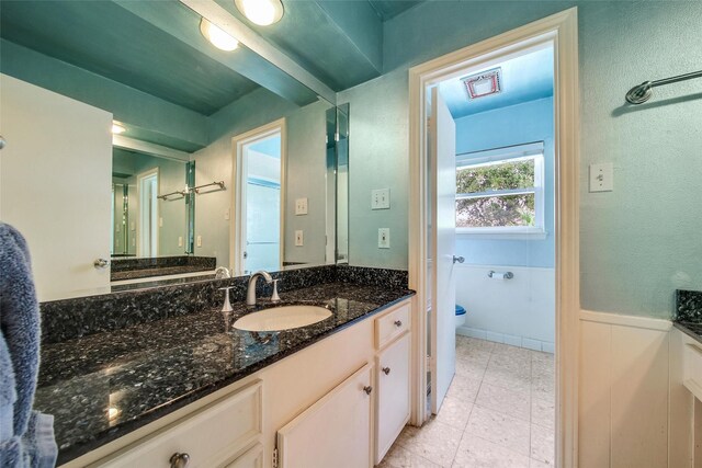 bathroom with a wainscoted wall, toilet, vanity, and visible vents