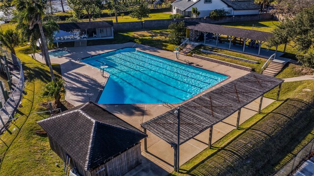 pool with an outbuilding, a storage structure, a patio area, and fence