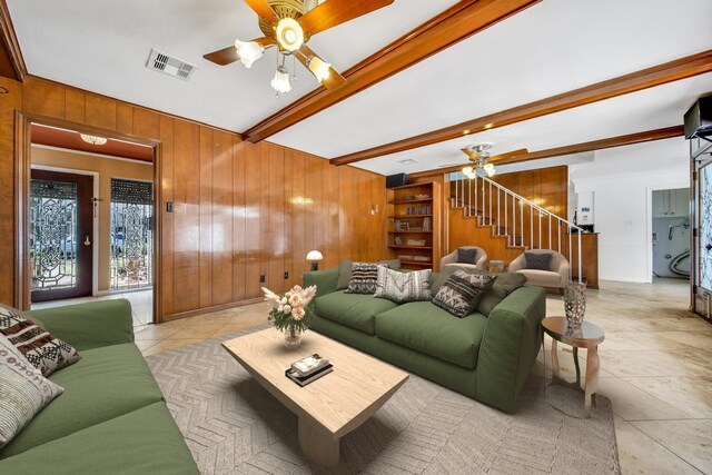 living room featuring visible vents, beamed ceiling, a ceiling fan, and wood walls