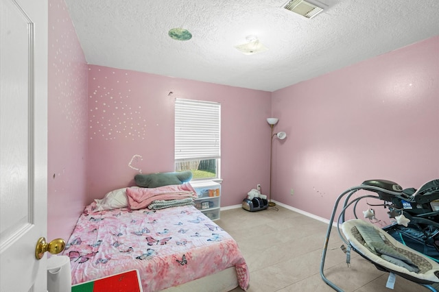 bedroom with visible vents, a textured ceiling, and baseboards