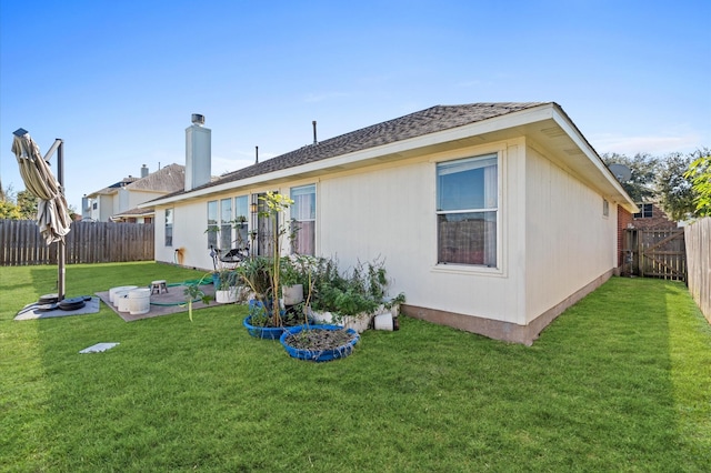 back of property with a fenced backyard and a lawn
