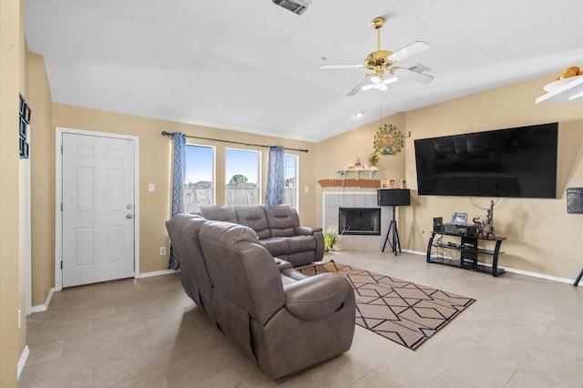 living room with ceiling fan, visible vents, baseboards, vaulted ceiling, and a tiled fireplace