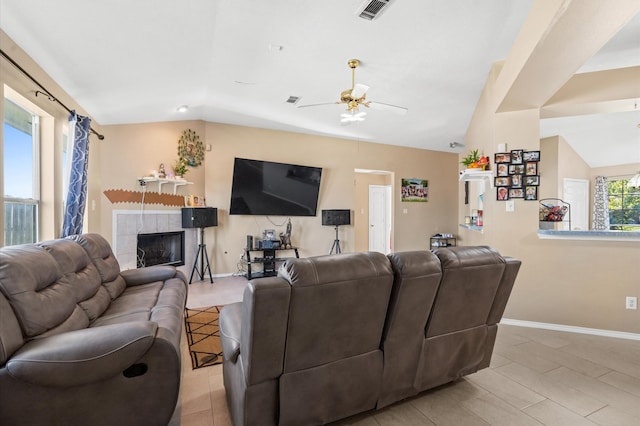 living room featuring baseboards, visible vents, a tiled fireplace, ceiling fan, and vaulted ceiling