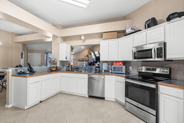 kitchen featuring a toaster, white cabinets, appliances with stainless steel finishes, backsplash, and dark countertops