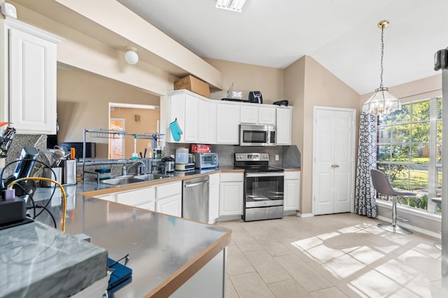 kitchen featuring light tile patterned flooring, stainless steel appliances, a sink, white cabinets, and backsplash