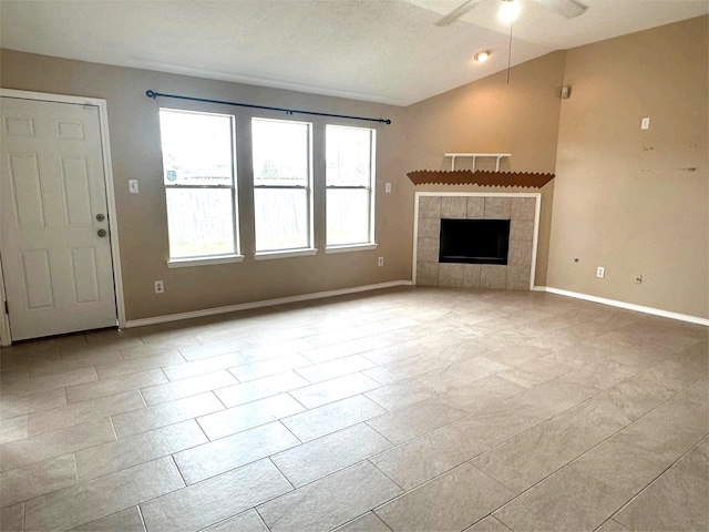 unfurnished living room with baseboards, lofted ceiling, a tile fireplace, and a ceiling fan