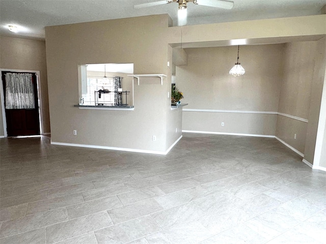 unfurnished living room featuring baseboards and a ceiling fan