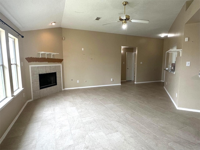 unfurnished living room with lofted ceiling, baseboards, visible vents, a ceiling fan, and a fireplace