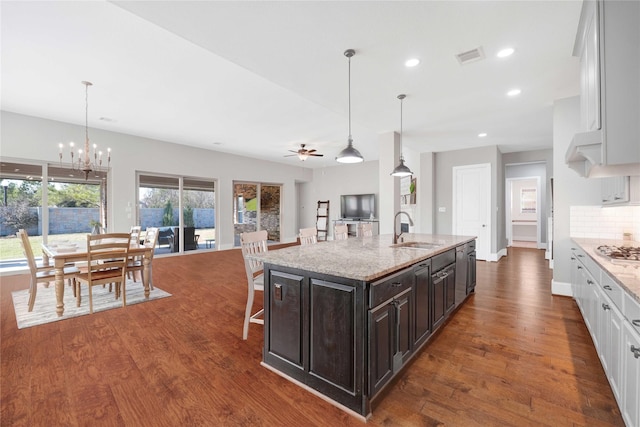 kitchen with tasteful backsplash, dark wood-type flooring, a sink, and white cabinetry