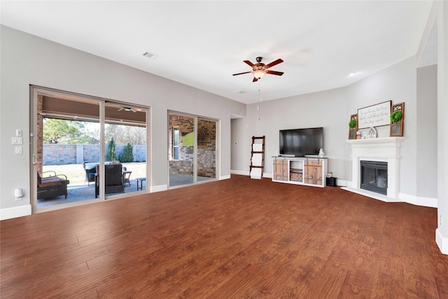 unfurnished living room featuring baseboards, a ceiling fan, wood finished floors, and a glass covered fireplace