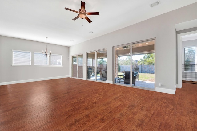 unfurnished living room with ceiling fan with notable chandelier, wood finished floors, visible vents, and baseboards