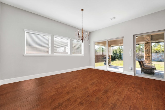 spare room with dark wood-style floors, a chandelier, visible vents, and baseboards