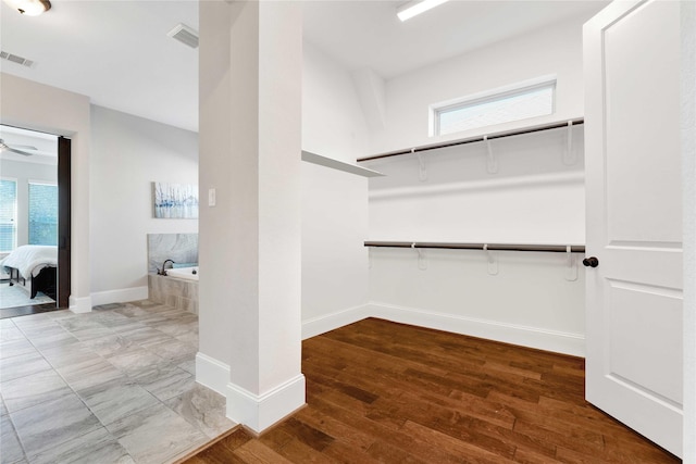 spacious closet with ceiling fan, wood finished floors, and visible vents