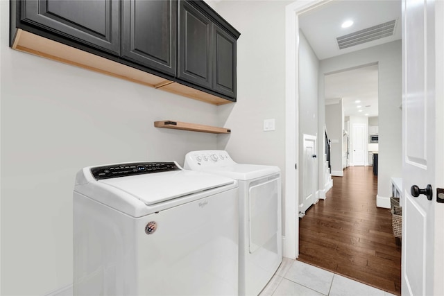 laundry area featuring cabinet space, light tile patterned floors, baseboards, visible vents, and separate washer and dryer