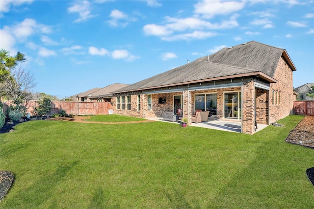 rear view of house with a fenced backyard, a lawn, and brick siding