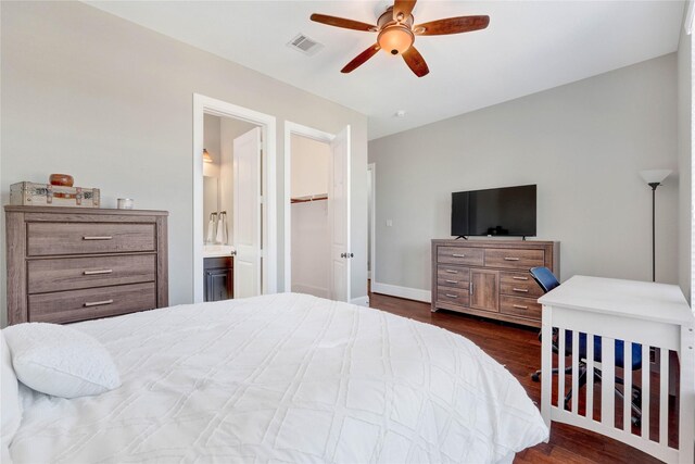 bedroom featuring visible vents, baseboards, dark wood-style floors, ensuite bath, and a spacious closet