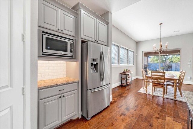 kitchen featuring stainless steel appliances, baseboards, backsplash, and hardwood / wood-style floors