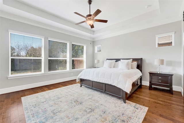 bedroom featuring baseboards, a raised ceiling, and dark wood finished floors