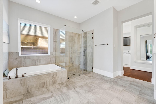 full bathroom with visible vents, baseboards, a bath, a stall shower, and washer / dryer