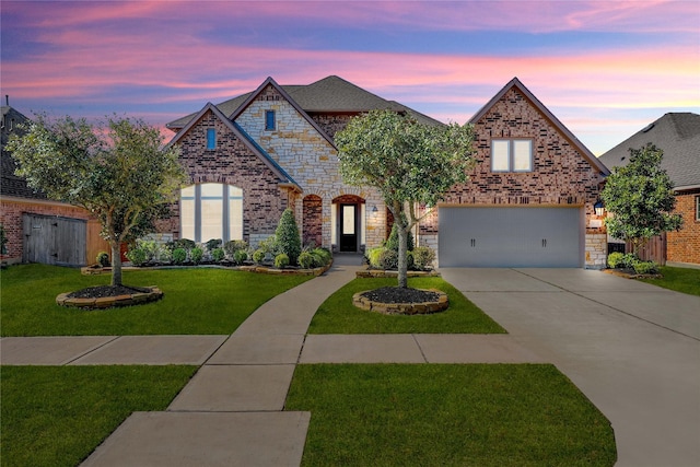 french country inspired facade with driveway, brick siding, an attached garage, and a front yard