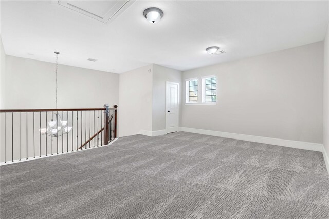 carpeted empty room with baseboards and a chandelier