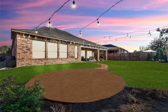 yard at dusk featuring fence and a patio