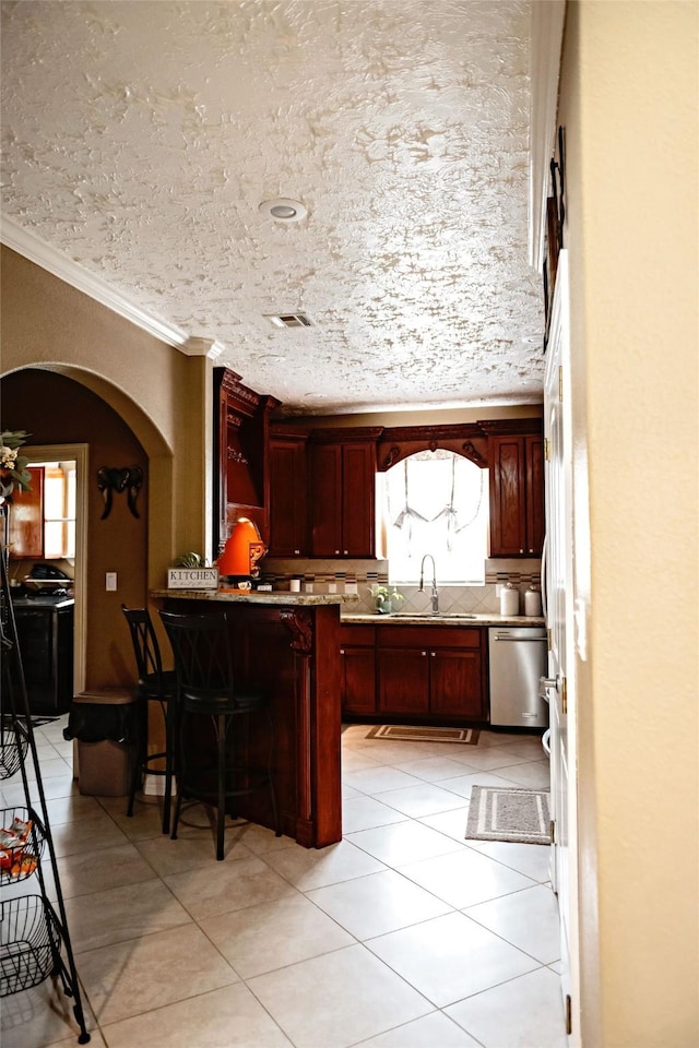 kitchen with arched walkways, a peninsula, a sink, dark brown cabinets, and dishwasher