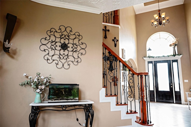 entryway with a chandelier, ornamental molding, stairway, and a towering ceiling