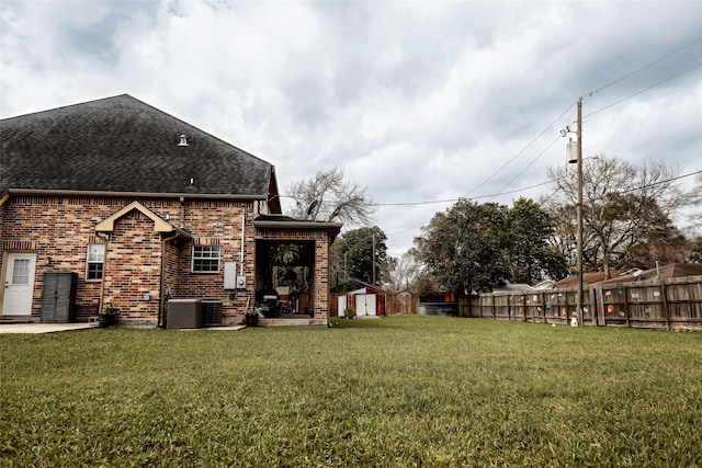 view of yard with a shed, fence, cooling unit, and an outbuilding