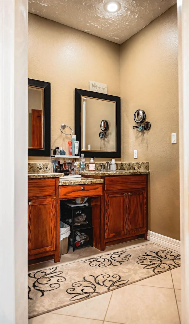 bathroom featuring double vanity, a textured ceiling, baseboards, and tile patterned floors