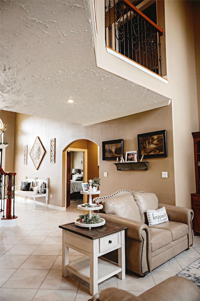 living room with arched walkways, stairway, a textured ceiling, and tile patterned floors