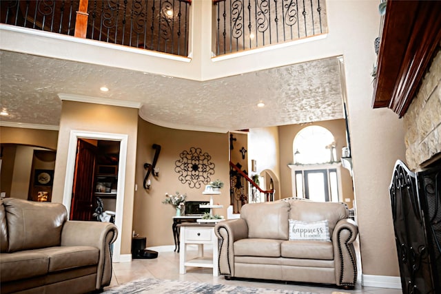 living room with light tile patterned flooring, crown molding, a towering ceiling, and baseboards