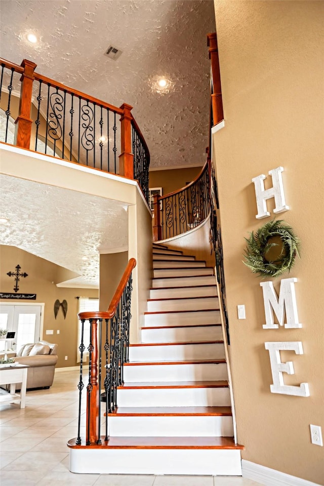 staircase featuring tile patterned flooring, visible vents, baseboards, and a textured ceiling