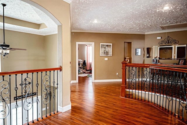 hall with attic access, arched walkways, ornamental molding, and wood finished floors