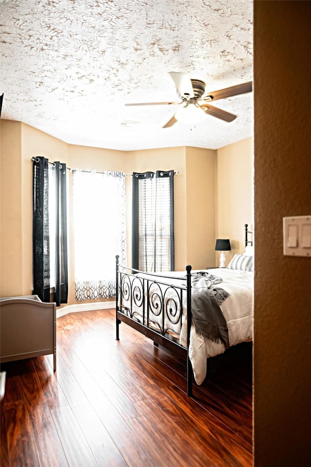 bedroom with a textured ceiling, wood finished floors, and a ceiling fan