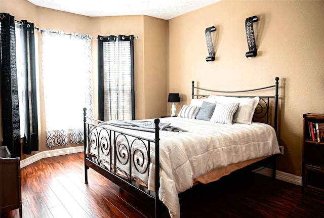 bedroom featuring a textured ceiling, baseboards, and wood finished floors